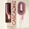 Cascadhe · hero-packshot-cream Brosse hydratante Cascadhe avec packaging cream et logo cardinal red, vue trois quarts