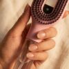 Cascadhe · in-hand-detail Main feminine tenant la brosse Cascadhe, gros plan sur le reservoir transparent