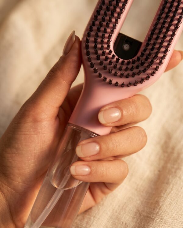 Cascadhe · in-hand-detail Main feminine tenant la brosse Cascadhe, gros plan sur le reservoir transparent